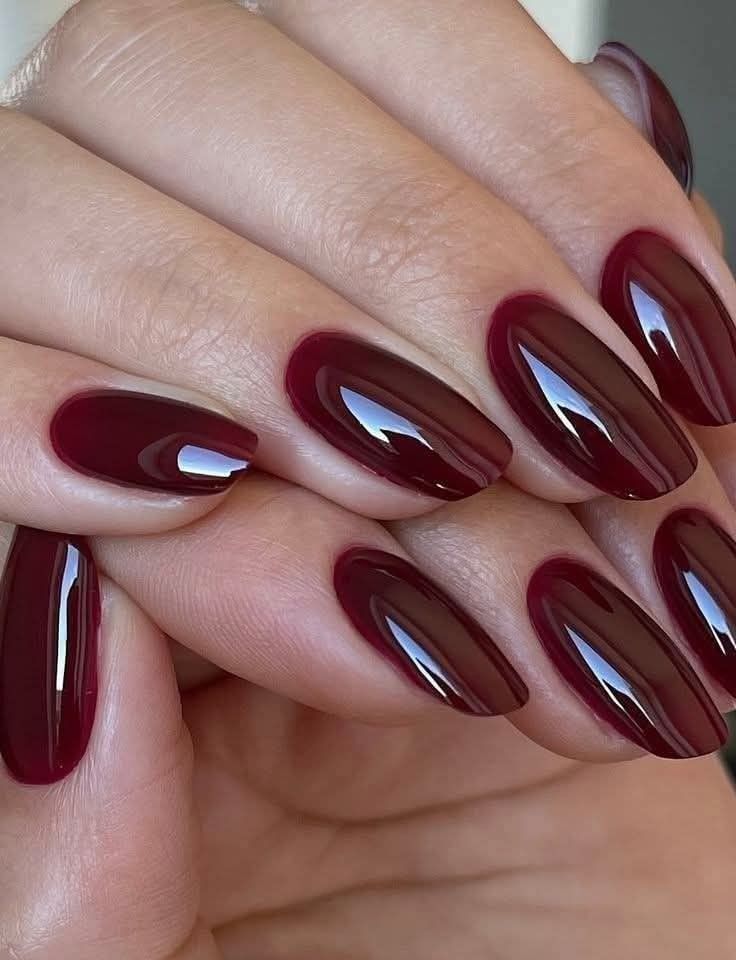 Glossy burgundy oval nails on both hands, deep wine red gel with a wet look shine
