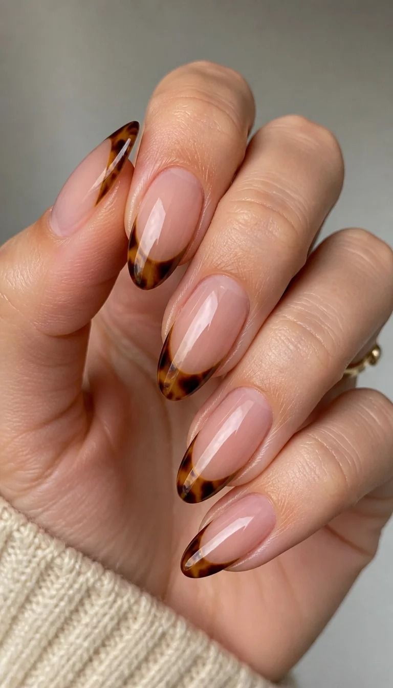 Tortoiseshell French tip nails with a sheer nude base and amber tortoise tips on almond nails