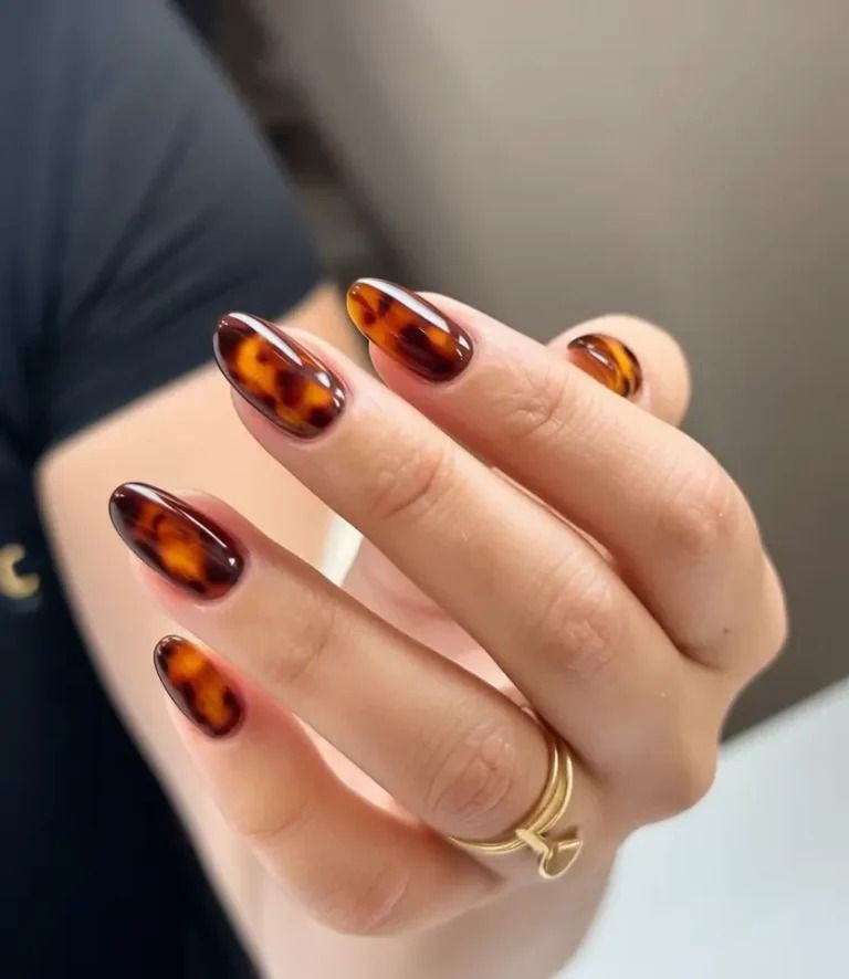 Classic tortoiseshell almond nails with amber and dark brown marbling on a glossy gel set