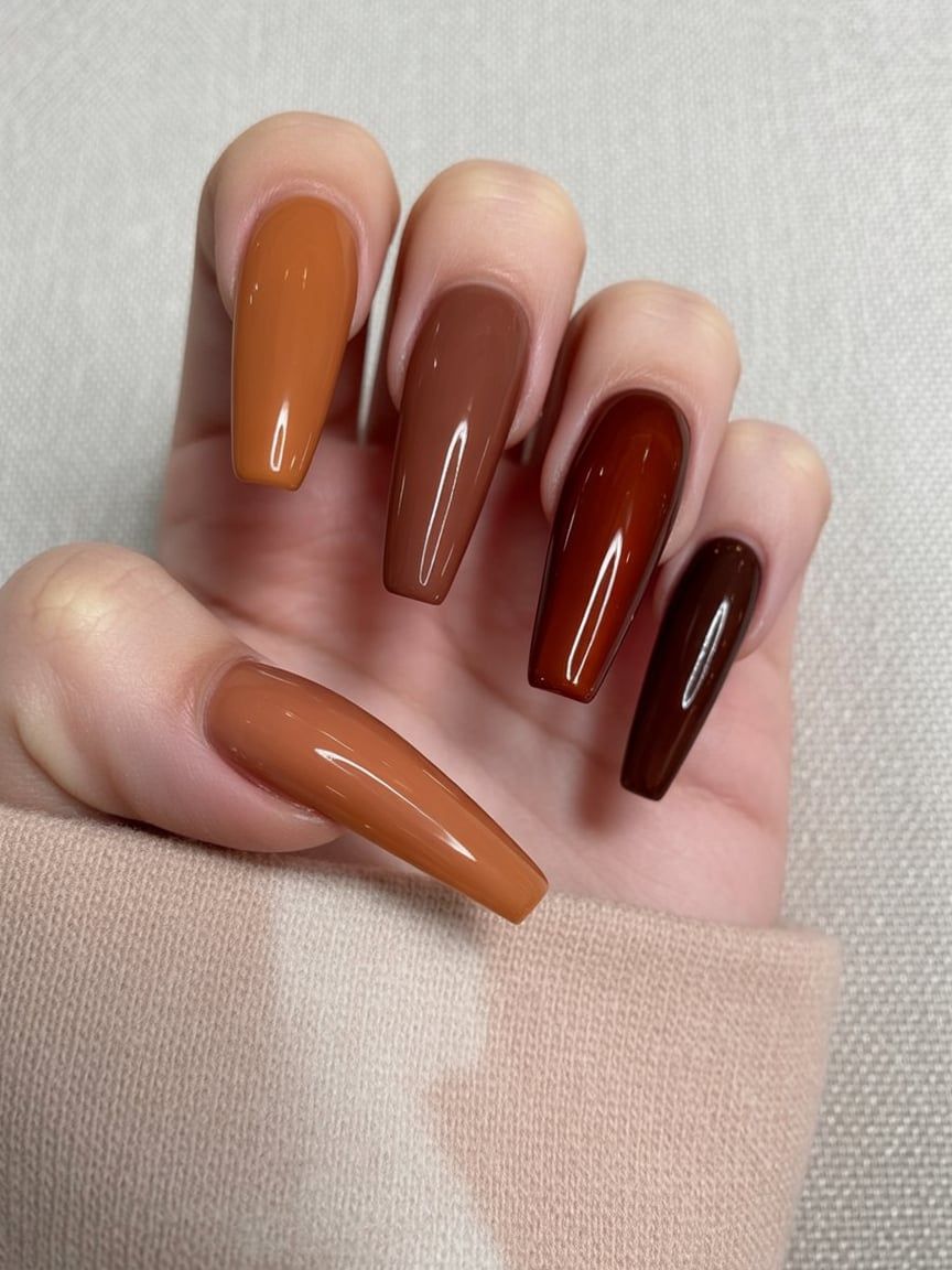 Multicolor coffin nails in caramel, chestnut and burgundy, each nail a different fall shade on long coffin nails